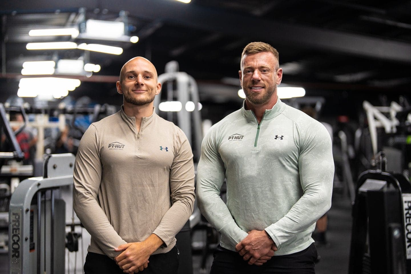 Daniel Marshall and Clinton Coffey, PT Hut's two tutors, standing side by side on a gym floor in PT-HUT tops